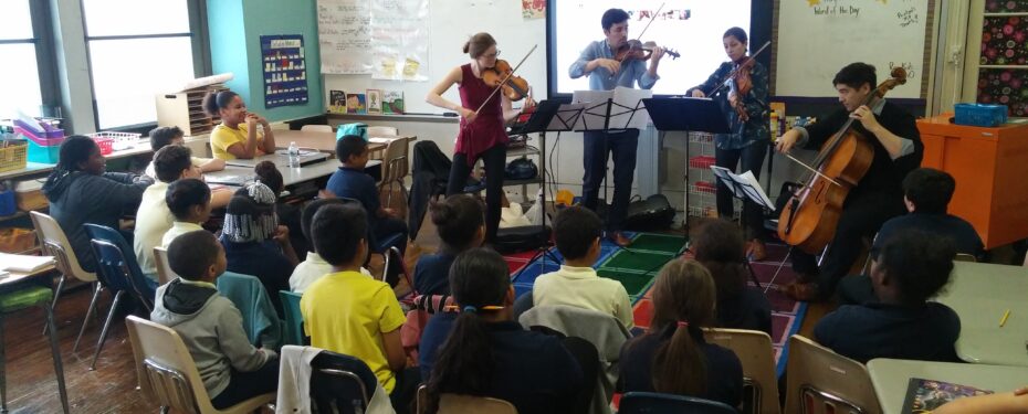 Students in their classroom facing string quartet performing